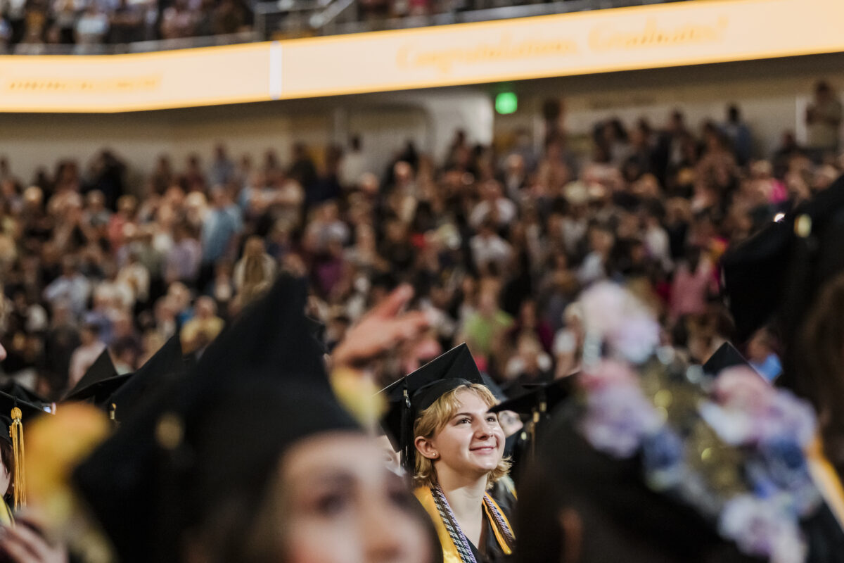 UMBC student during Spring 2024 commencement. Student is looking ahead with a slight smile and is the focal point in image. 