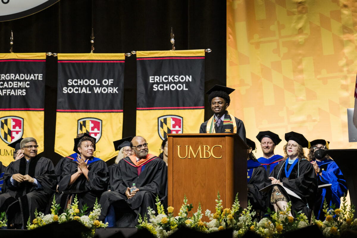 UMBC Valedictorian of the College of Natural and Mathematical Sciences; College of Engineering and Information Technology; and Division of Undergraduate Academic Affairs afternoon ceremony co-valedictorian, D'Juan Moreland, addressing the audience during Commencement. He is standing a podium on stage delivering his speech.