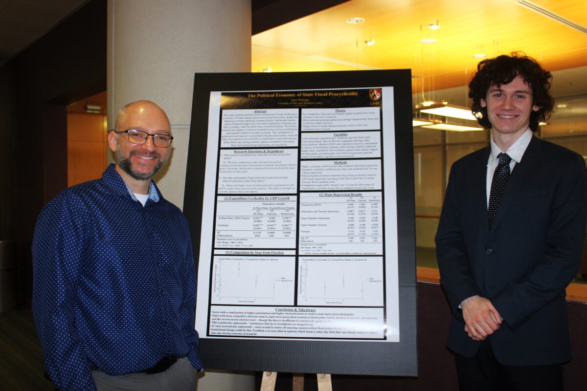 Peter Wilschke and a professor stand on each side of a research poster
