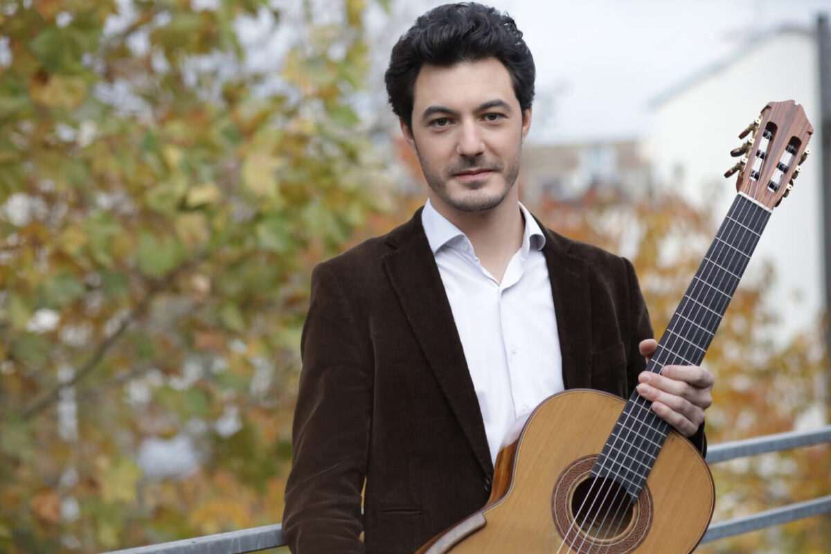 A man poses with a classical guitar.