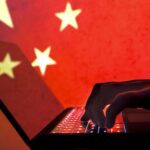 China Hands typing on a lap top with a red background and gold stars China
