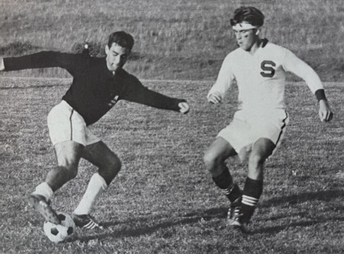 in a black and white photo, two men play soccer