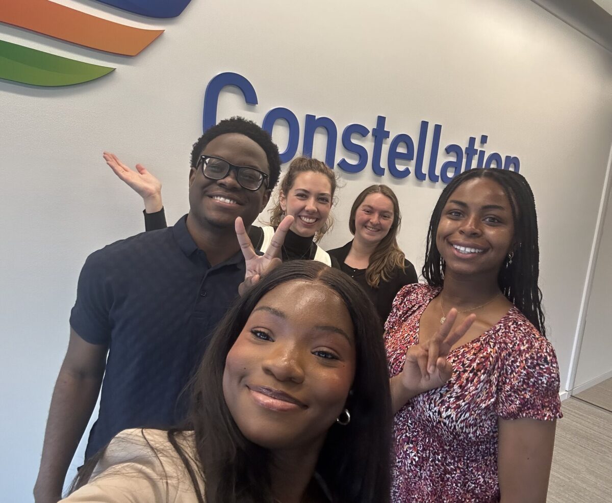 Group of students take a selfie in front of a Constellation sign.