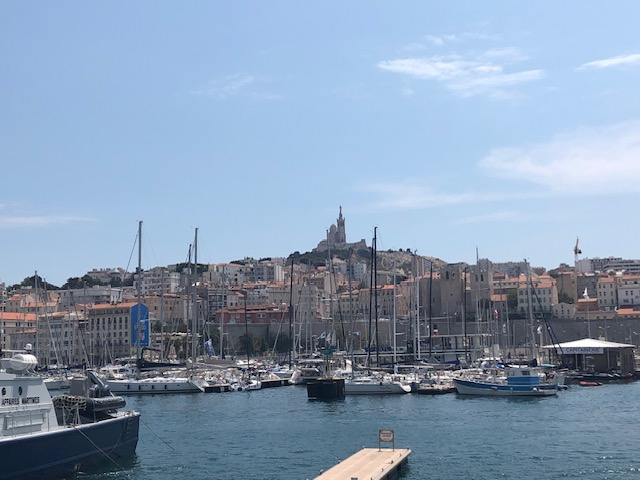 A seaport in Marseille, France in the Mediterranean with a view of a grand cathedral at the top of a hill.