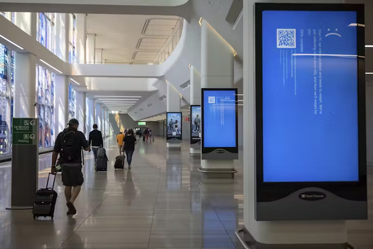 People with suitcases walk past blue screen at airport