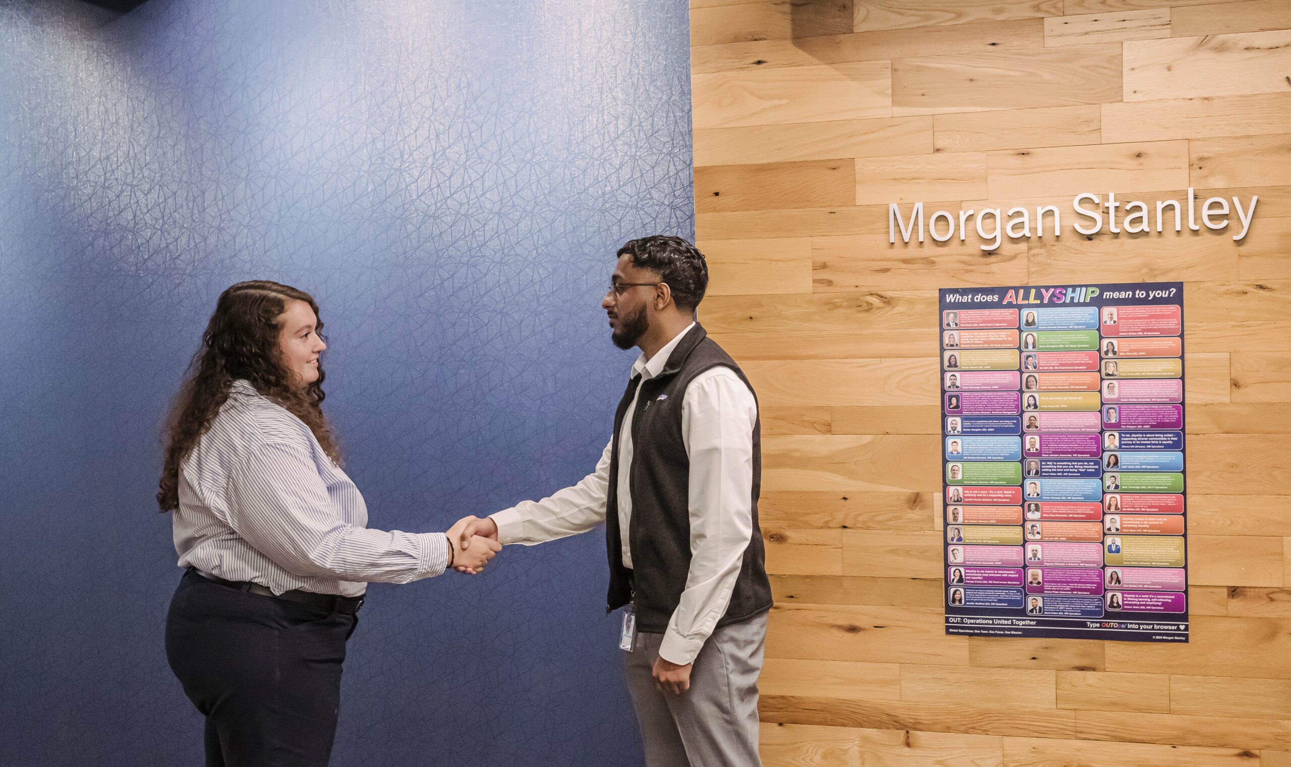 A umbc student Anil Shaji (right) shaking hands with internship supervisor Rachel Hanrahan. Both are standing in front of a backdrop that has the Morgan Stanley logo in the back.