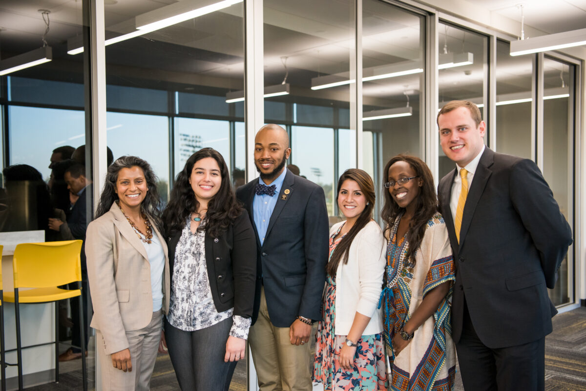 Four public school educators stands together in between two university administrators posing for an event photo 