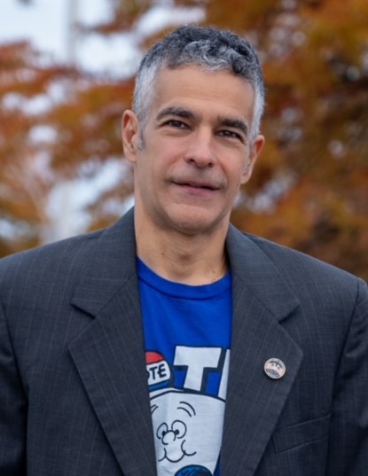 A person wearing a navy suit jacket over a blue t-shirt.