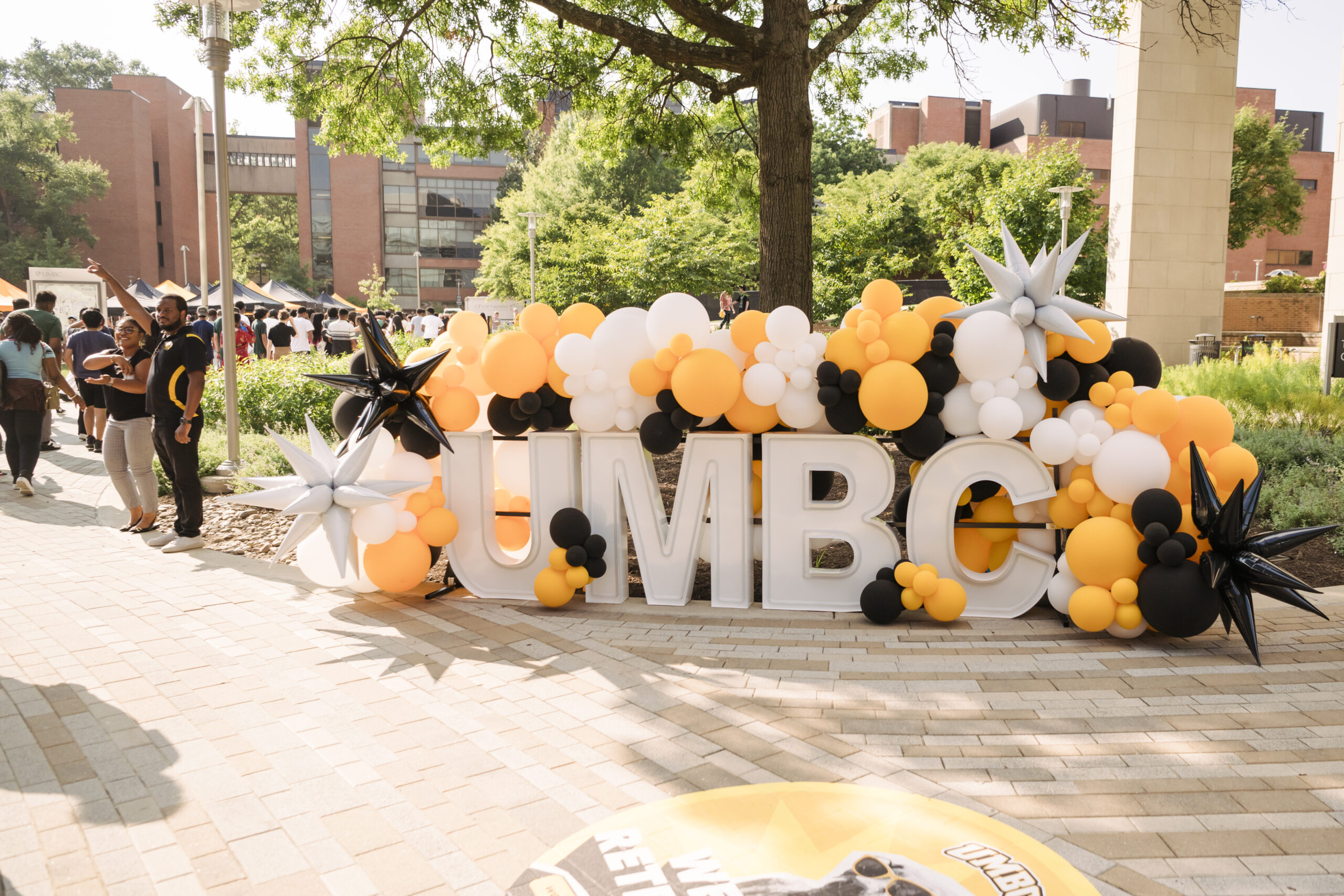 large cutout letters of UMBC propped up with black and gold and white balloons surrounding