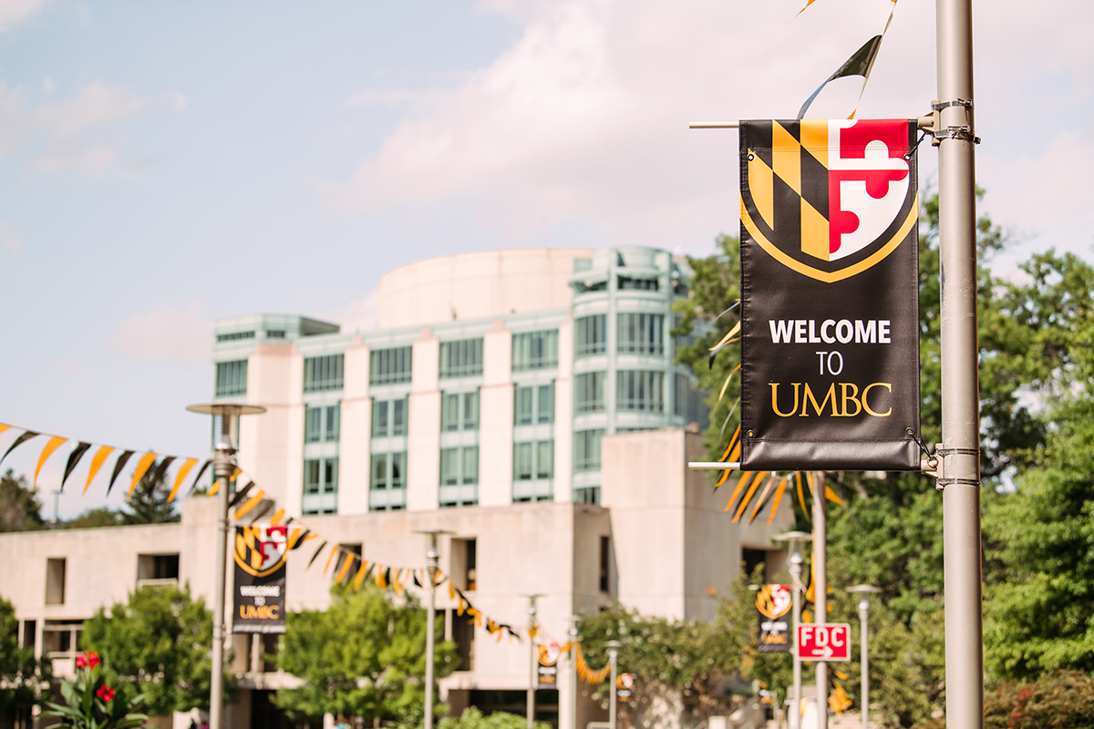 Welcome to UMBC flag with UMBC's AOK library and campus