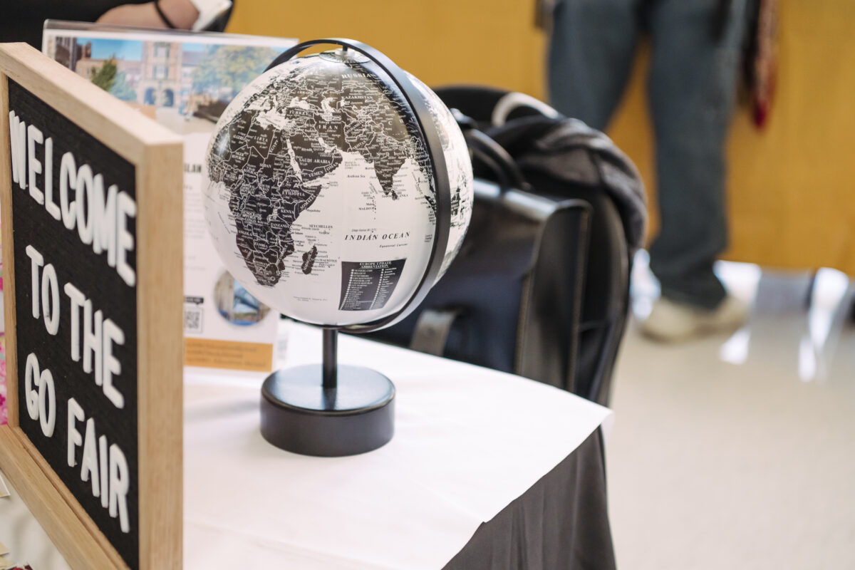 A black and white globe sits on a table with a sign "welcome to the go fair: