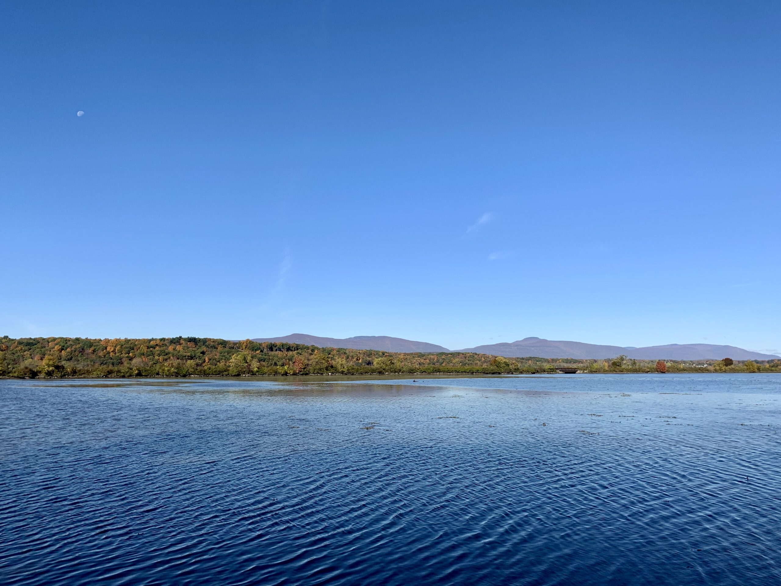 A view across a river to another shore, with sky overhead.