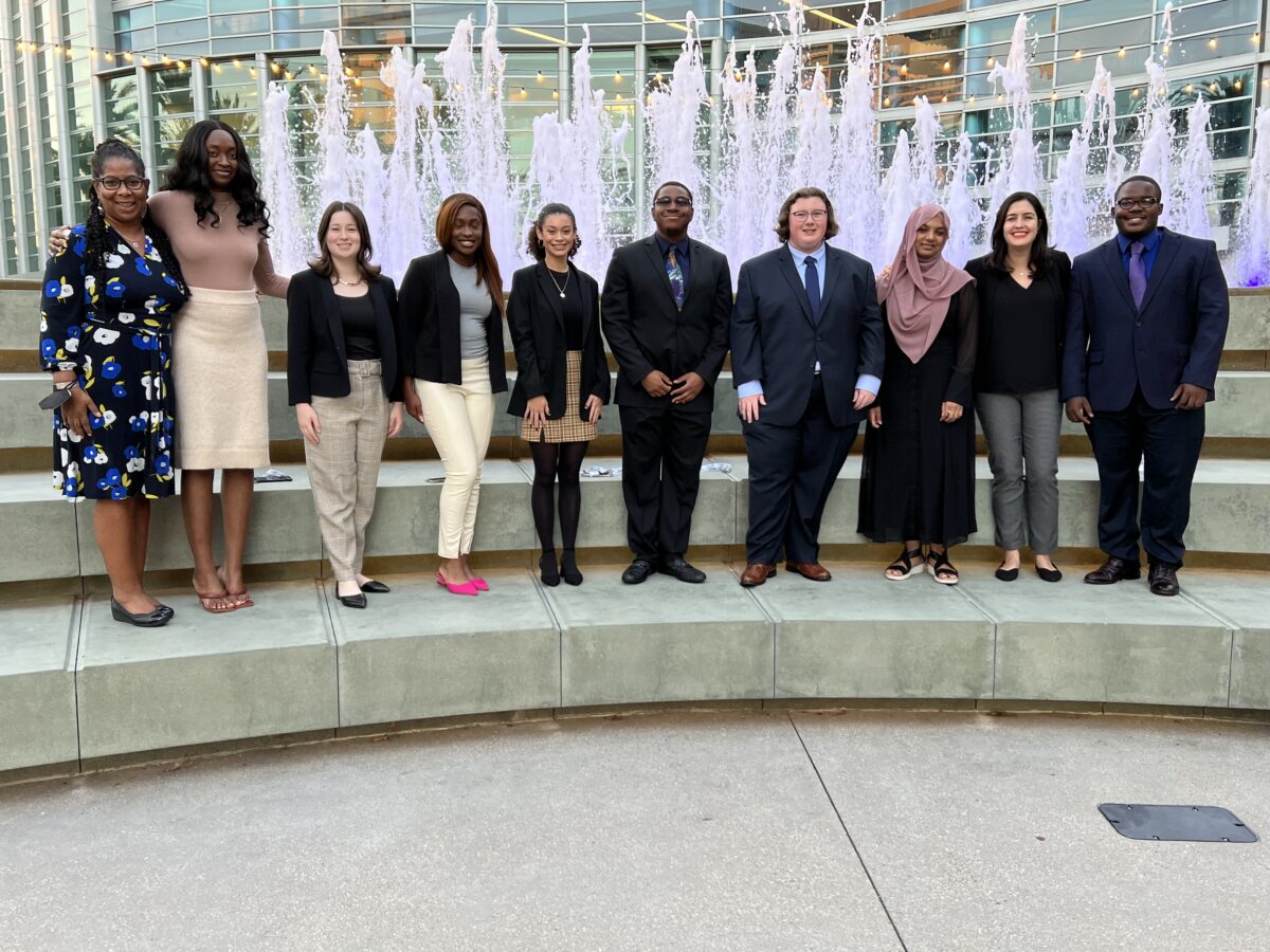 group photo of 10 people dressed professionally standing in front of a fountain