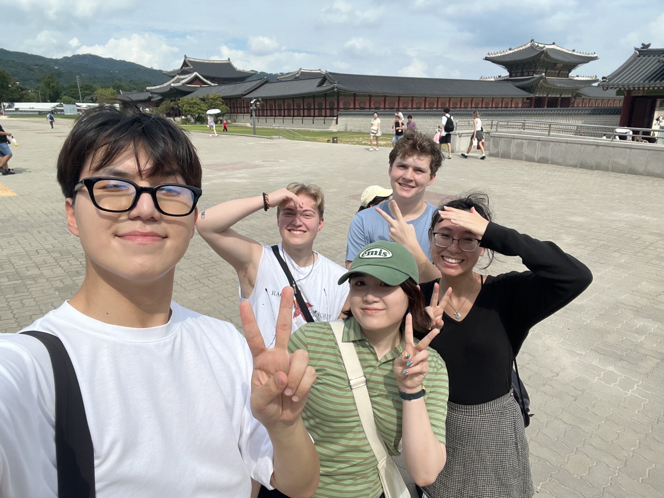 a group of young people make the peace sign and stand in front of the National Palace Museum of Korea