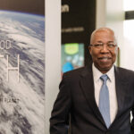 Man standing who is wearing a suit and tie, smiling at the camera at NASA Goddard Space Flight Center