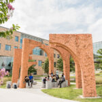 Large orange cement arches in front of a building on a college campus ethics