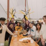 a group of umbc alums gathering in the alumni and friends tent during homecoming 2024