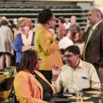 A gym filled with business people speaking to each other Great Colleges to Work For