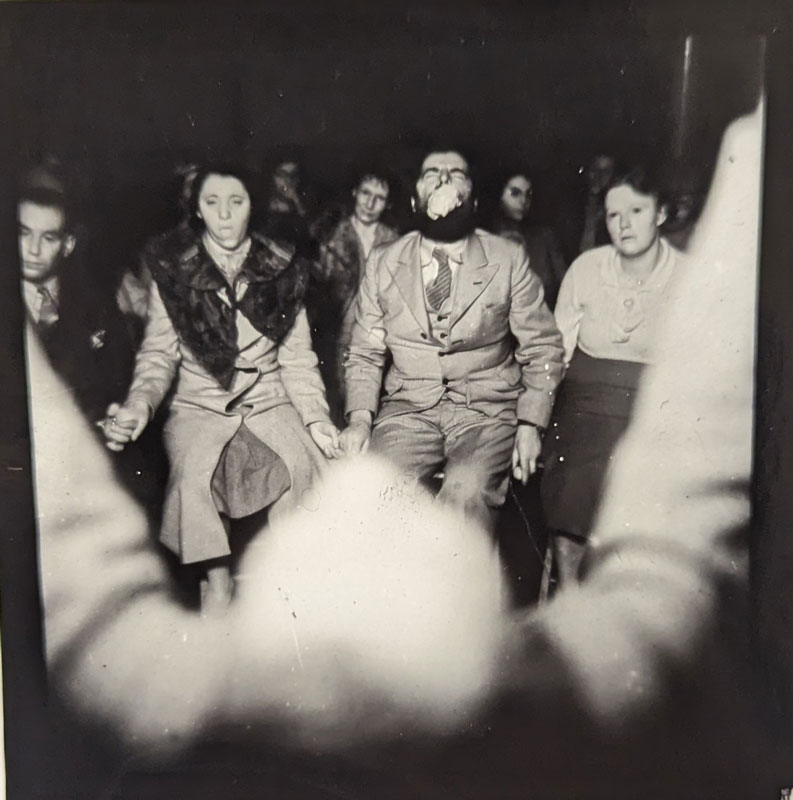 A black and white image of people participating in a parapsychology event.