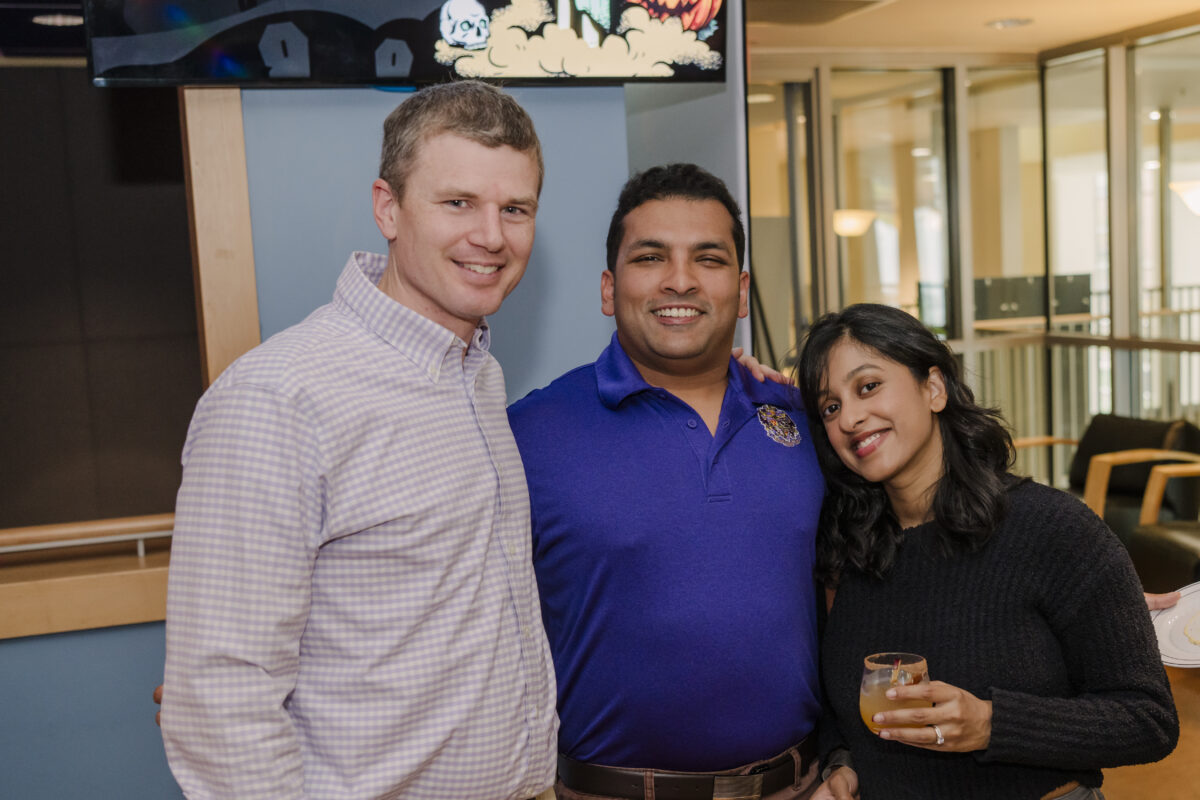 three umbc alums during the greek alumni party. one person on the right is holding a drink in a glass. 