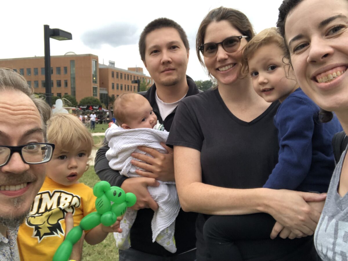 Four adults and three young kids pose for a selfie.