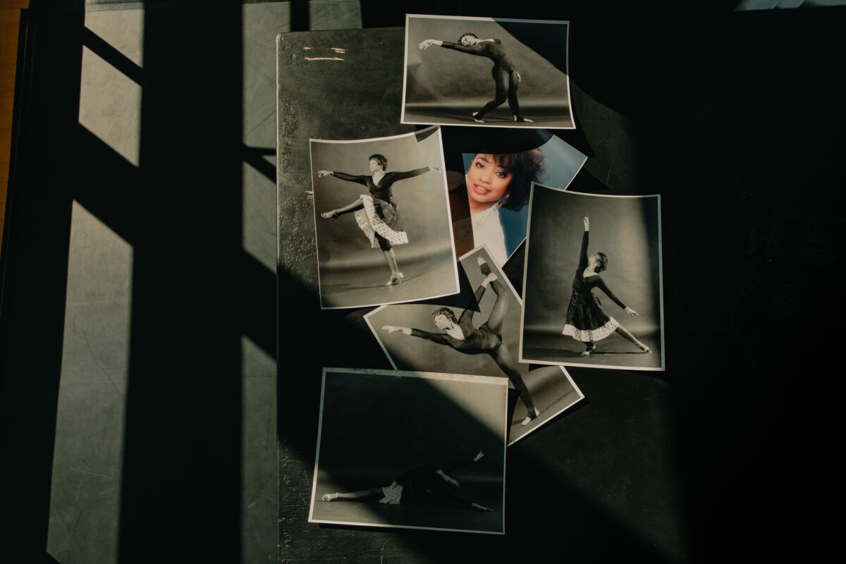 A collection of black-and-white photographs of Teresa in various elegant dance poses. These pictures are laid out on a dark surface. Sunlight comes in through large windows, which gives an artsy effect due to the geometric shadows the appear across the photos. Towards the center and behind some photos is a headshot of a younger Teresa, the only picture in color.