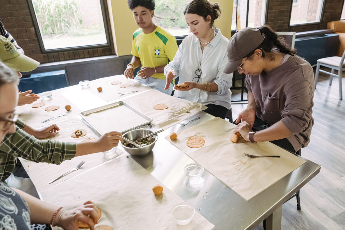 Students scoop sauteed mushrooms to fill a dough pocket and seal the edges to make a meat pie