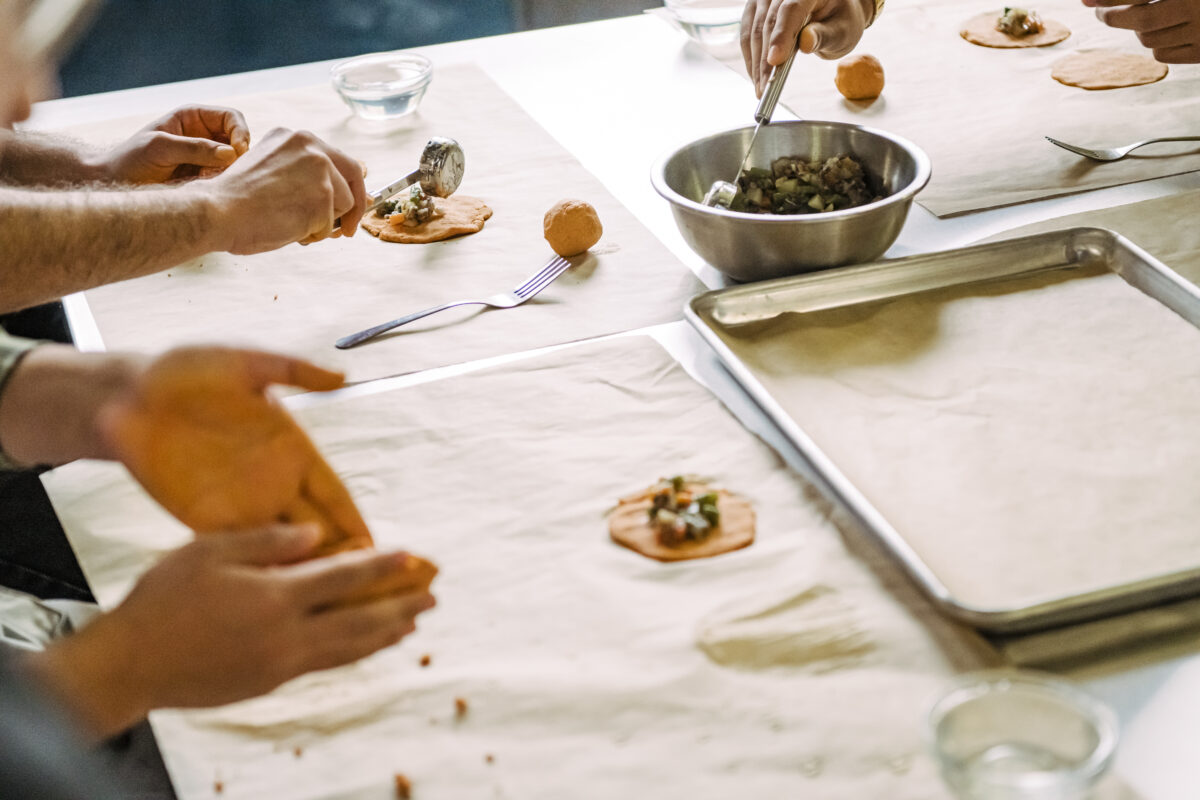 Students scoop sauteed mushrooms to fill a dough pocket to make Salvadoran pastelitos