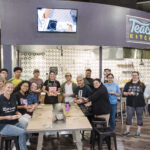 UMBC college students gather at True Grits' Test Kitchen holding small plates of Salvadoran pastelitos with chef Karla T. Vasquez