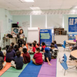 A student-teacher leads an elementary classroom in circle-time