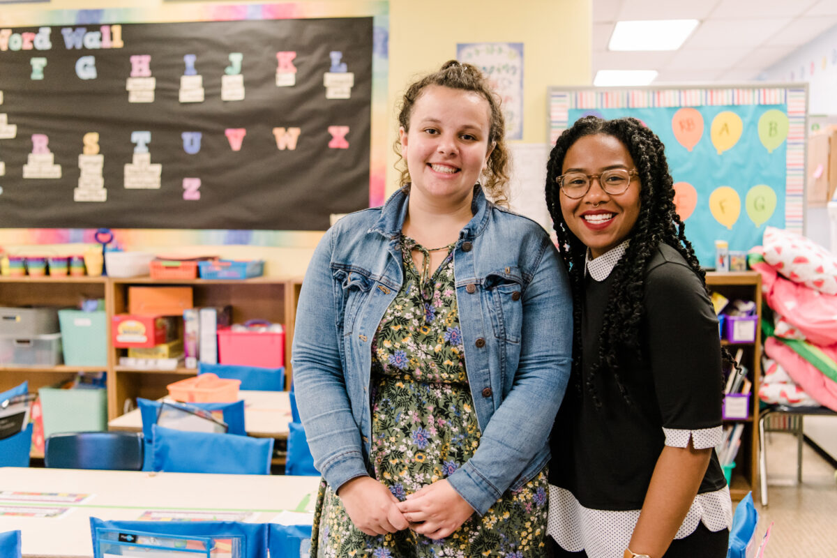 Two elementary school teachers stand next to each other inside a classroom MSDE