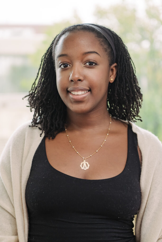 headshot of a woman with a black headband smiling with a necklace on