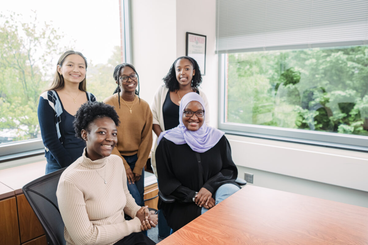 A group of five students poses for camera in conference room.