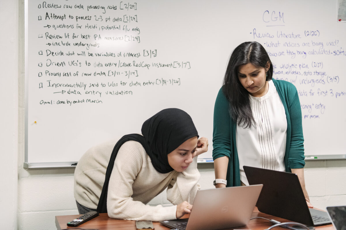 Tasneem Khambaty works with a graduate student analyzing data on a lap top