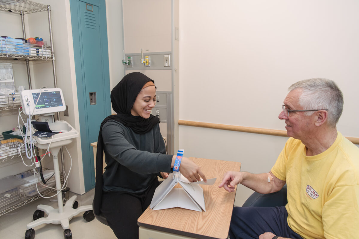 A graduate student sits at a table across from a patient showing them with a flip book