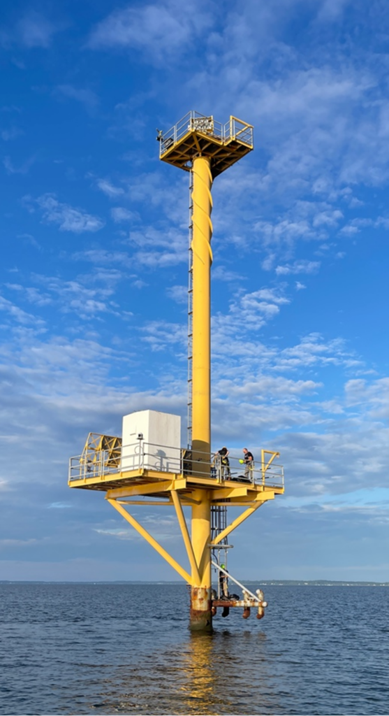 a tall vertical yellow column surrounded by water; a large lower platform near the surface and a much smaller upper platform very close to the top