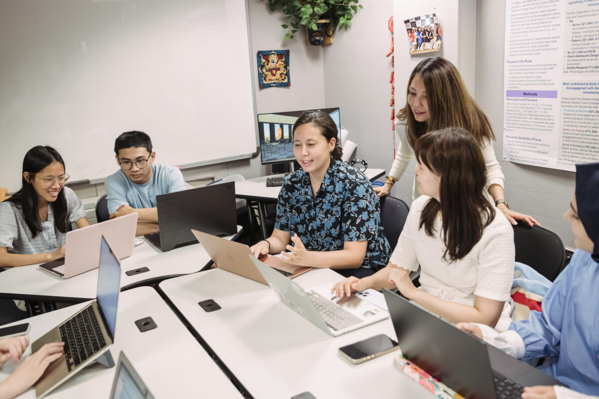 Charissa Cheah and students gather around a table to discuss psych research