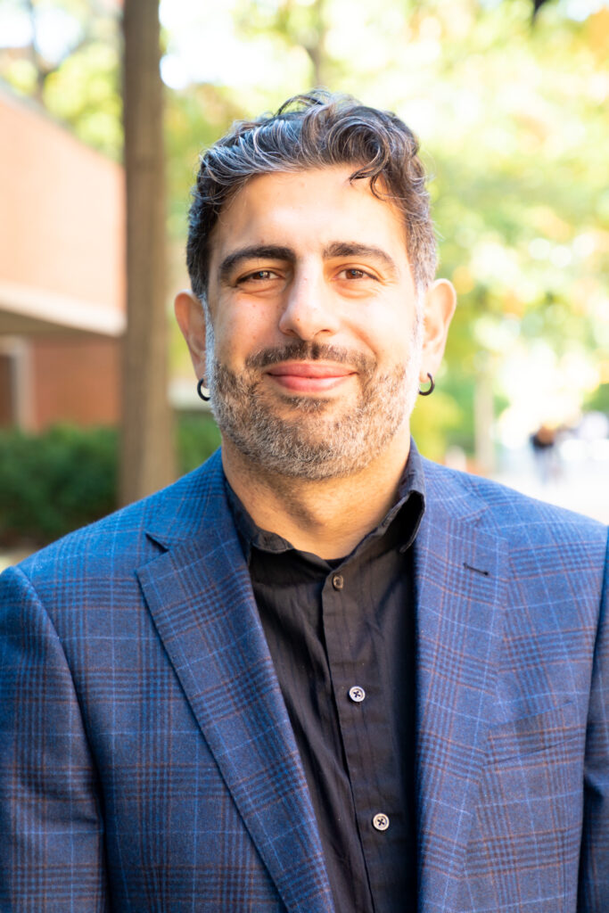 Head shot of a man in button-up shirt and coat.