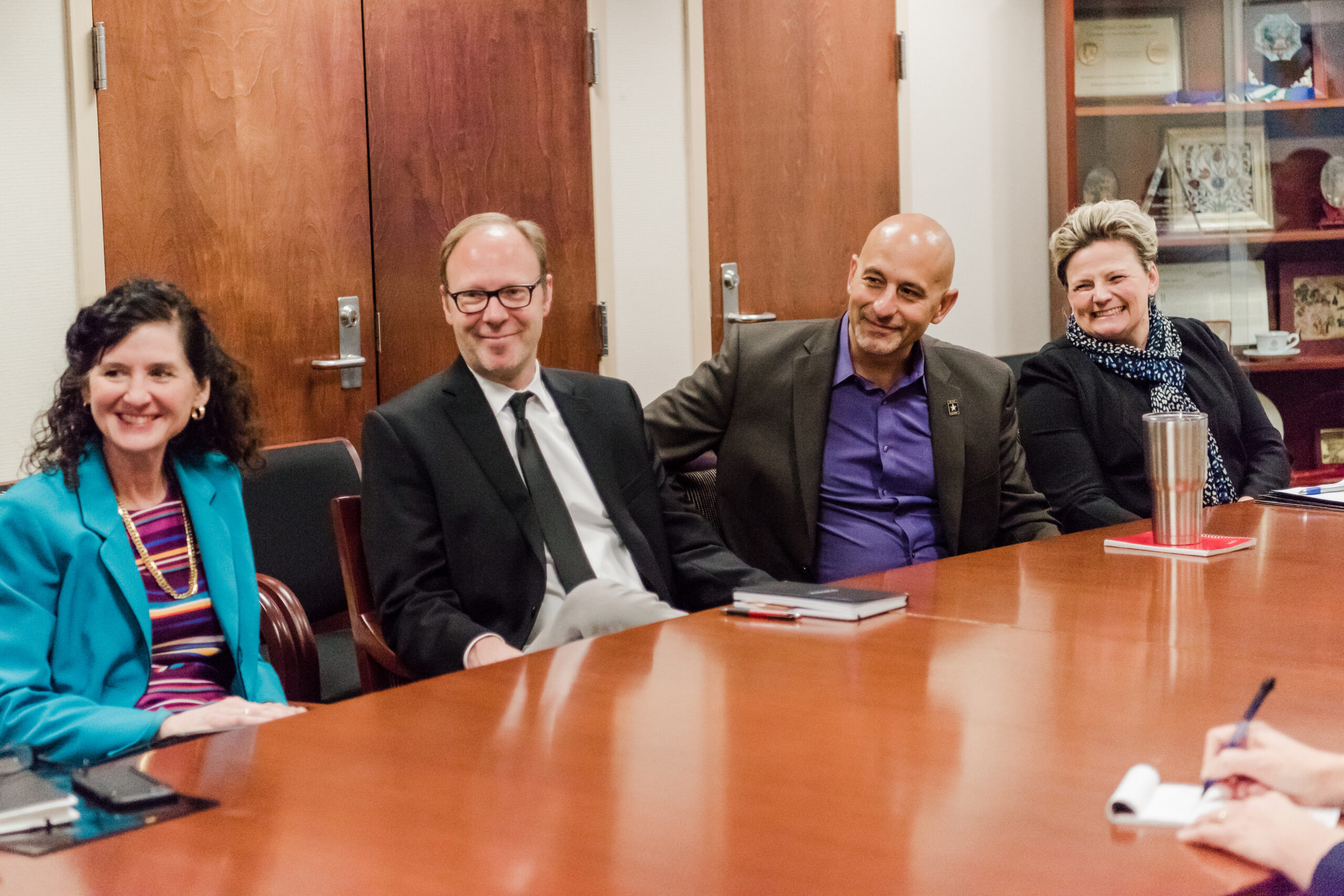 a group of people sit around a conference table with smiles on their faces. Malwitz is second from left, he often tries to bring creativity to the technology world