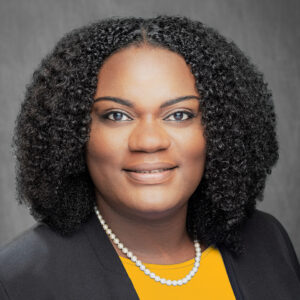 Portrait of Tiffany Tucker wearing a gold shirt and black blazer representing UMBC's colors