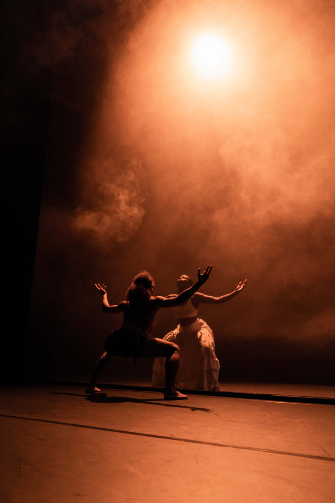 In a monochromatic image, two dancers perform on a stage.