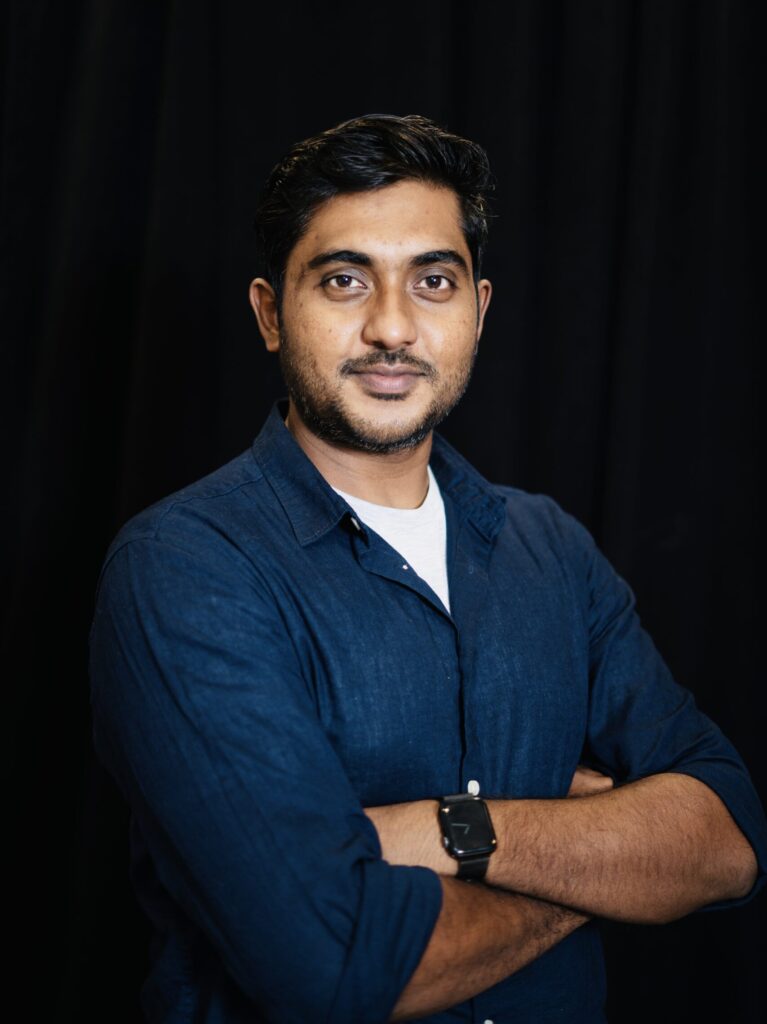 black background; portrait of man with arms crossed