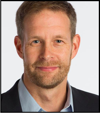 Derek Hyra, a white man with short brown hair, wears a blue shirt and dark jacket.