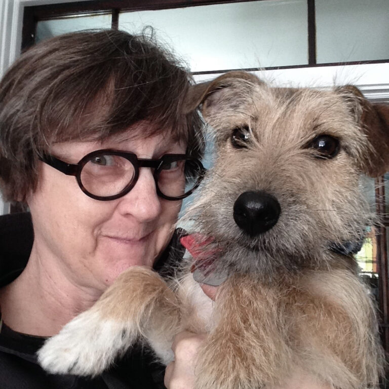 Susan McCully, a white woman wearing glasses, poses with a terrier.