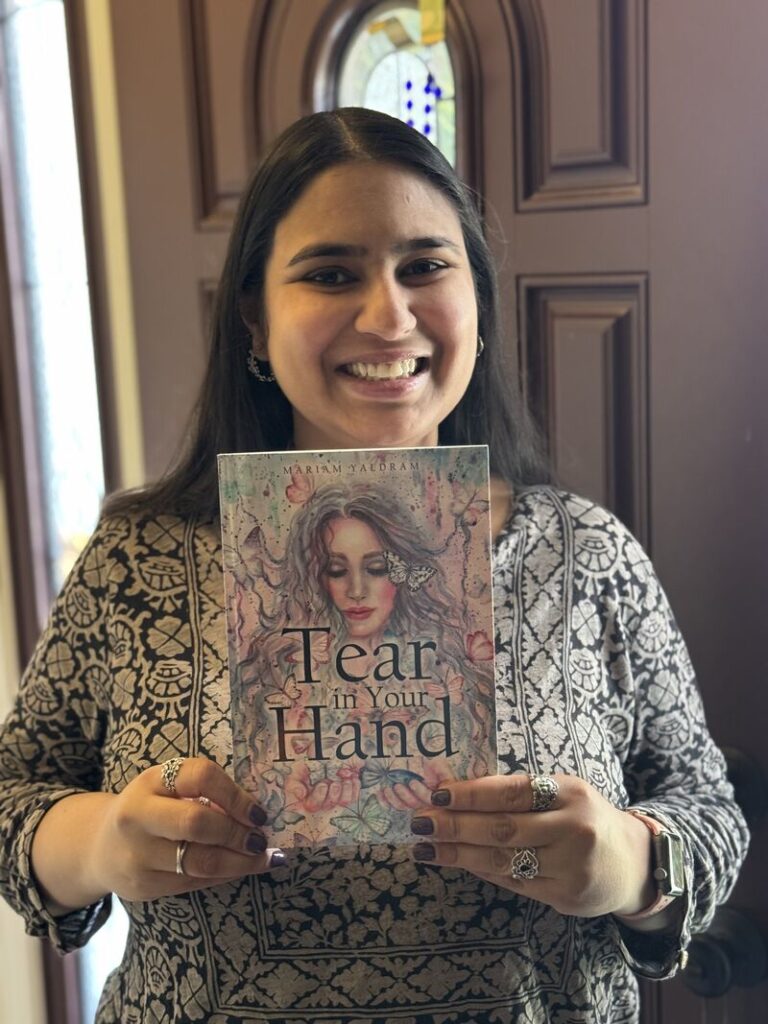 Yaldram holding her deut novel, "Tear in Your Hand."