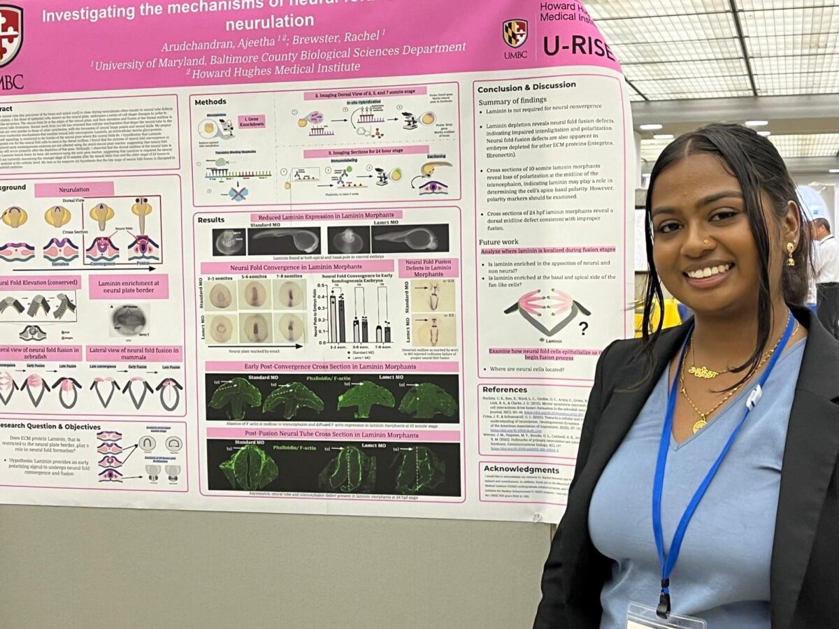 young woman stands next to research poster