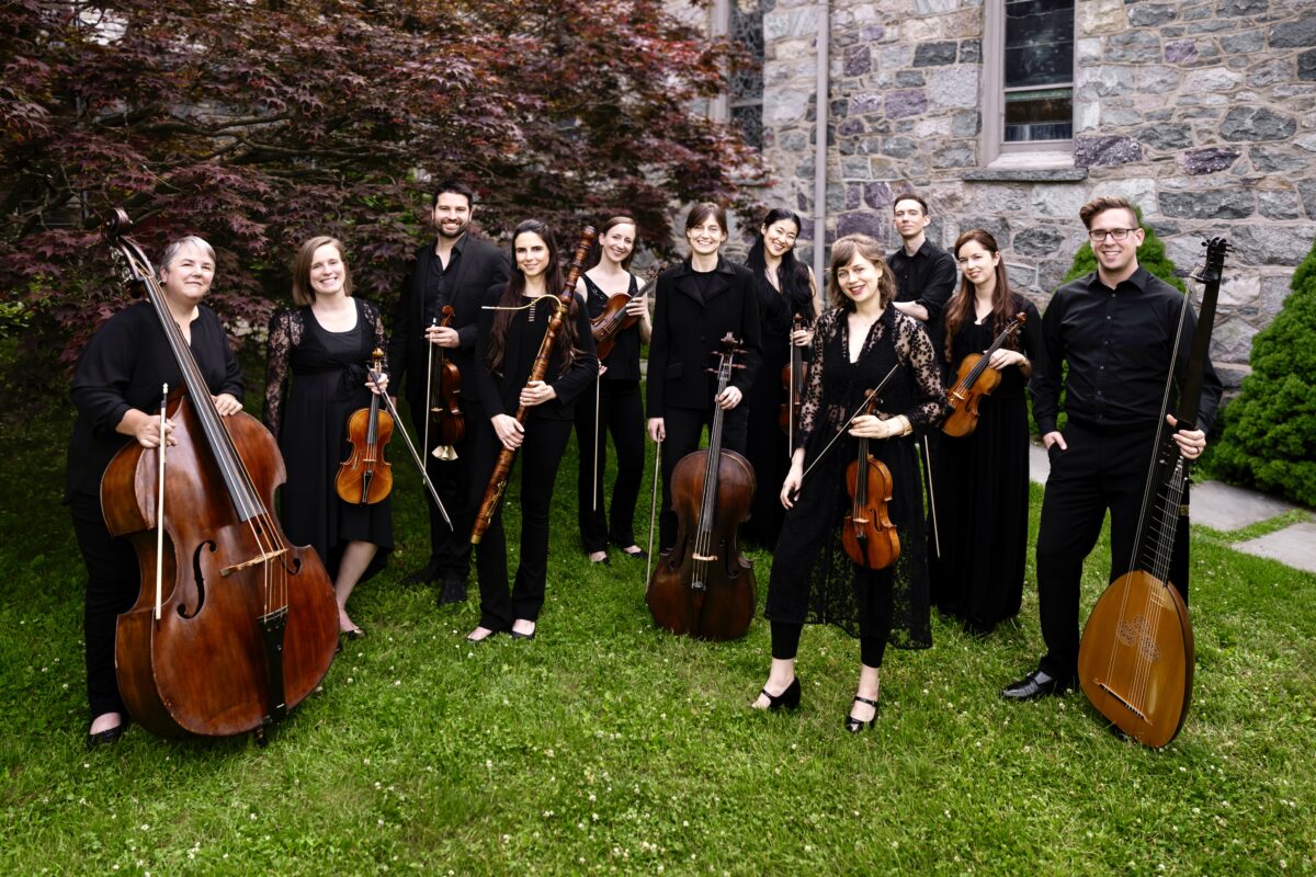 An ensemble of eleven musicians poses with string instruments.