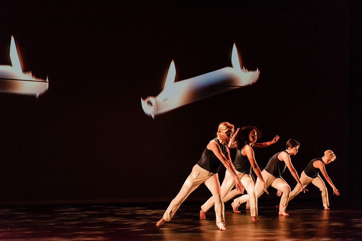 dance students on stage performing with a projected backdrop displaying candles