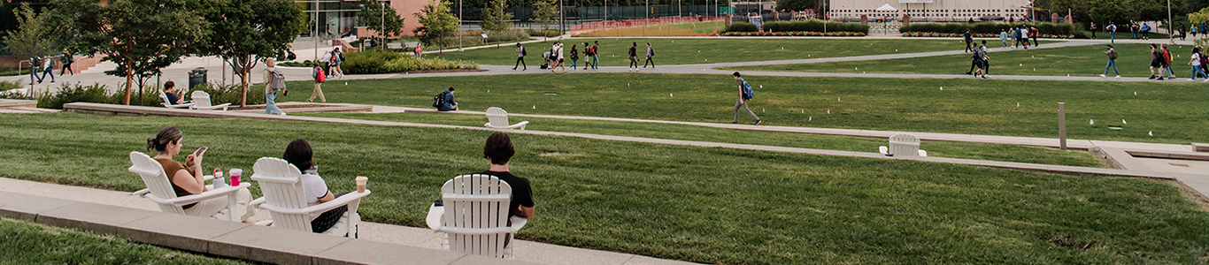 students sitting outside on lawn chairs, overlooking the green lawn