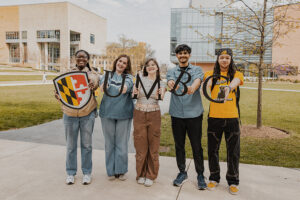 a diverse group of students holding up the UMBC maryland shield and letters